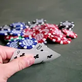Playing cards held over poker chips